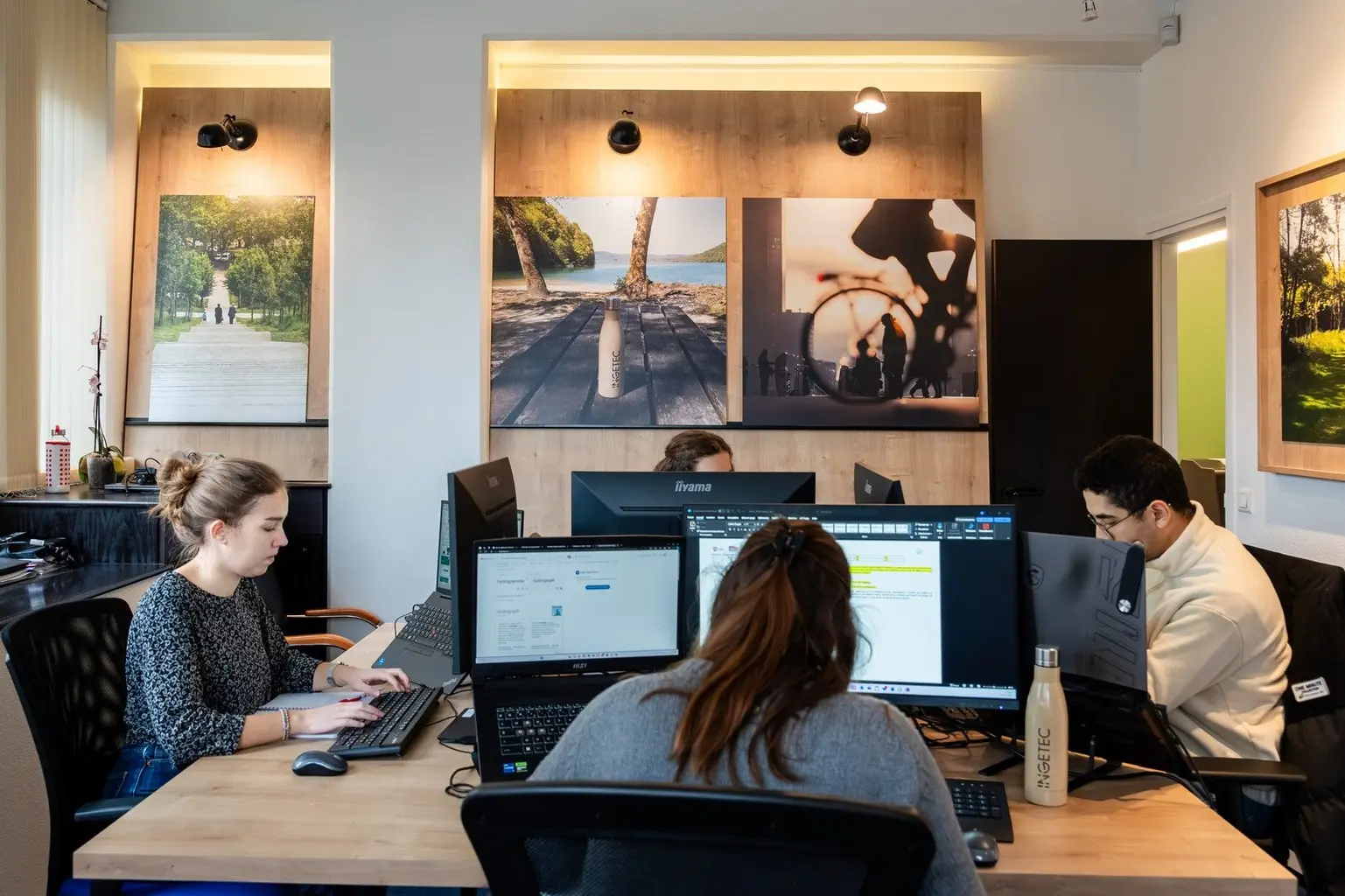 Équipe concentrée travaillant sur des ordinateurs dans un bureau moderne, décoré avec des photographies inspirantes